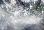 Satellite view of Sumatra, the Malay Peninsula and western Borneo on October 16, 2026 under a grey-white veil of cloud and haze, with coastlines outlined