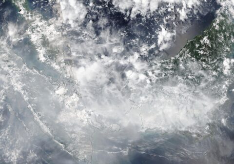 Satellite view of Sumatra, the Malay Peninsula and western Borneo on October 16, 2026 under a grey-white veil of cloud and haze, with coastlines outlined