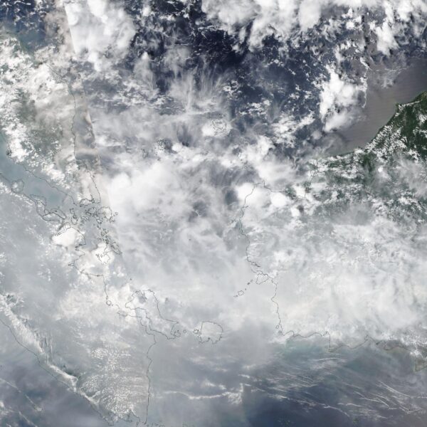 Satellite view of Sumatra, the Malay Peninsula and western Borneo on October 16, 2026 under a grey-white veil of cloud and haze, with coastlines outlined