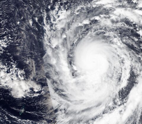 Satellite view of Super Typhoon Champi's cloud mass and eye just west of Guam, whose coastline is outlined at right