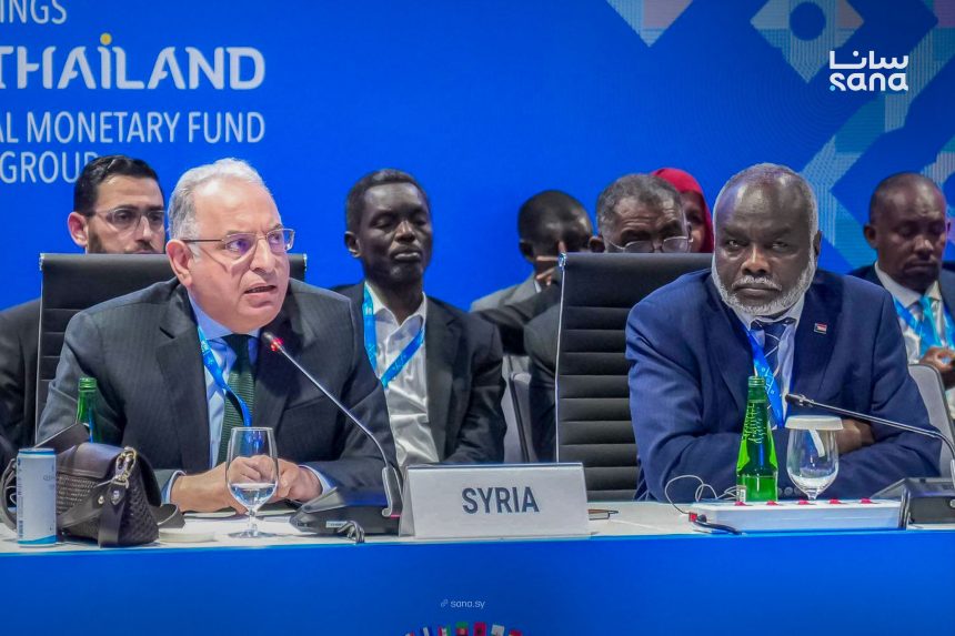 A delegate speaks behind a Syria nameplate at a session of the 2026 IMF and World Bank annual meetings in Bangkok