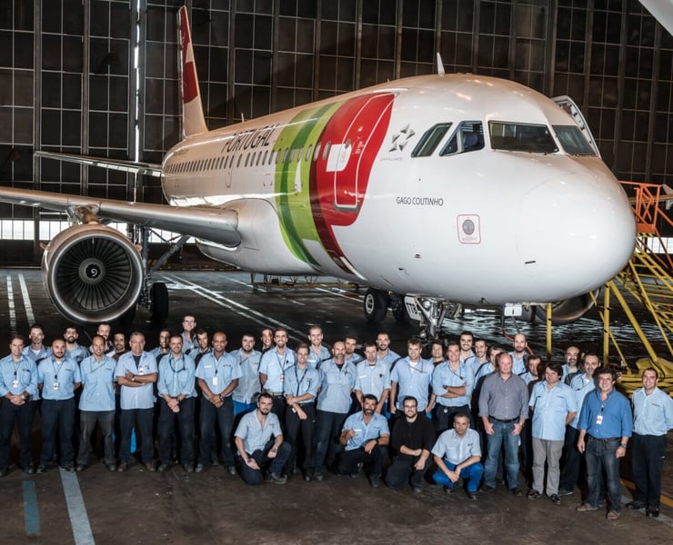 TAP Air Portugal maintenance and engineering staff posing with an Airbus A320 inside a hangar