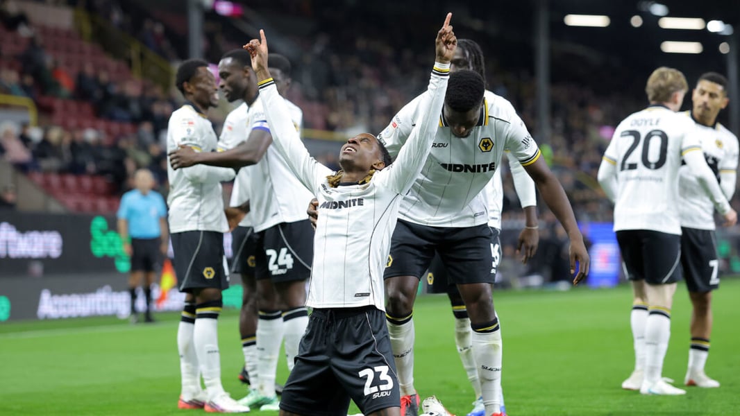 Wolves substitute Tawanda Chirewa kneels with both arms raised as team-mates celebrate around him at Turf Moor