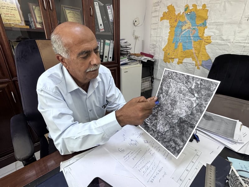Taybeh Mayor Suleiman Khourieh points to a map of the closed military zone around the West Bank town