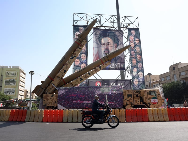A motorist passes missiles displayed beside a billboard in Tehran.