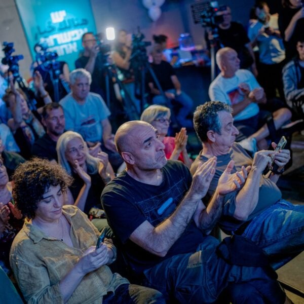 Attendees applaud and film on phones at an election campaign meeting in Tel Aviv ahead of Israel's October 27 vote