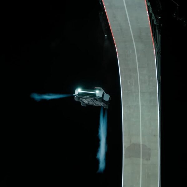 Tesla Roadster prototype flying through the night sky beside a curved ramp, with cold-gas thruster plumes, at the October 15, 2026 unveiling in McGregor, Texas