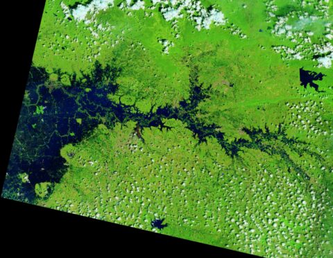 False-color Landsat image of Thailand with dark blue floodwater filling a river valley amid green vegetation