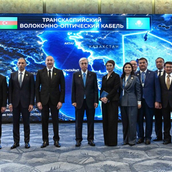 Presidents Tokayev and Aliyev with officials in front of a map of the Trans-Caspian fiber-optic cable in Baku