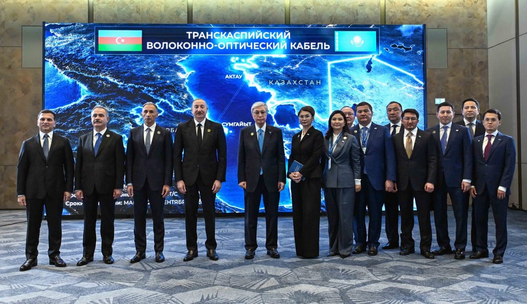 Presidents Tokayev and Aliyev with officials in front of a map of the Trans-Caspian fiber-optic cable in Baku