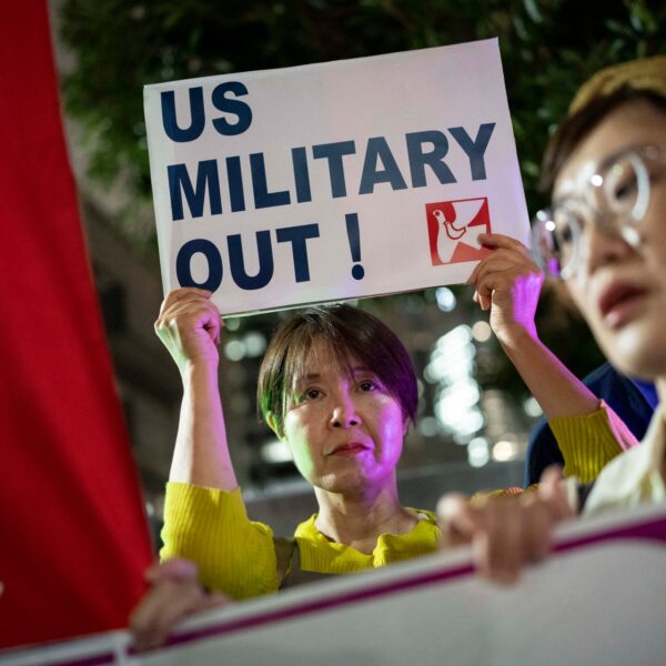Protesters hold a US Military Out sign outside the Prime Minister's Office in Tokyo after a US Marine was arrested over the killing of a woman in Okinawa