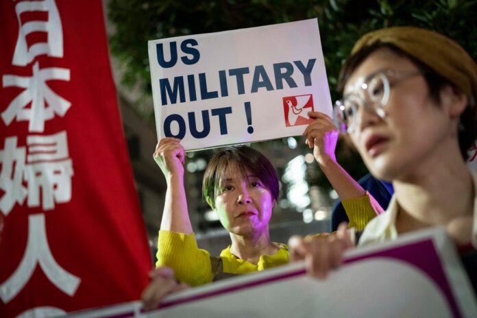 Protesters hold a US Military Out sign outside the Prime Minister's Office in Tokyo after a US Marine was arrested over the killing of a woman in Okinawa