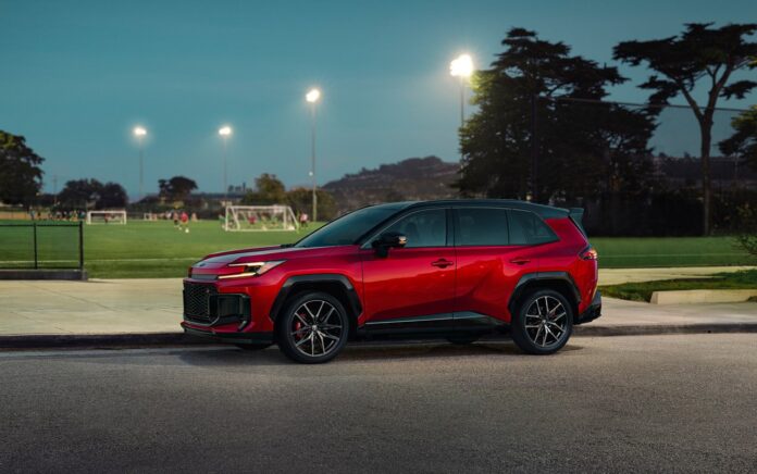 A red 2026 Toyota RAV4 Plug-in Hybrid GR Sport parked at dusk beside a floodlit sports field