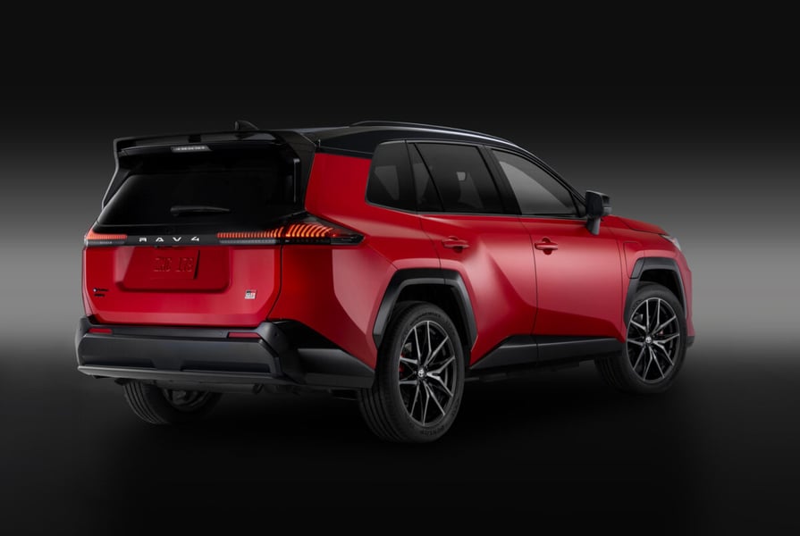 Rear three-quarter studio view of a red 2026 Toyota RAV4 Plug-in Hybrid GR Sport with a black roof