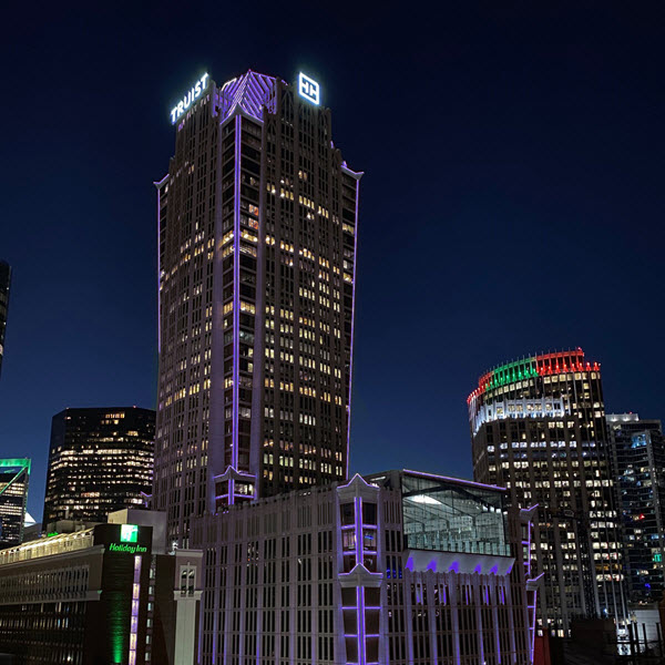 Truist Center tower in Charlotte lit in purple at night with the Truist sign on its crown