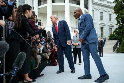 President Trump leans toward a crowd of reporters and microphones on the White House South Lawn, with Mike Tyson standing beside him