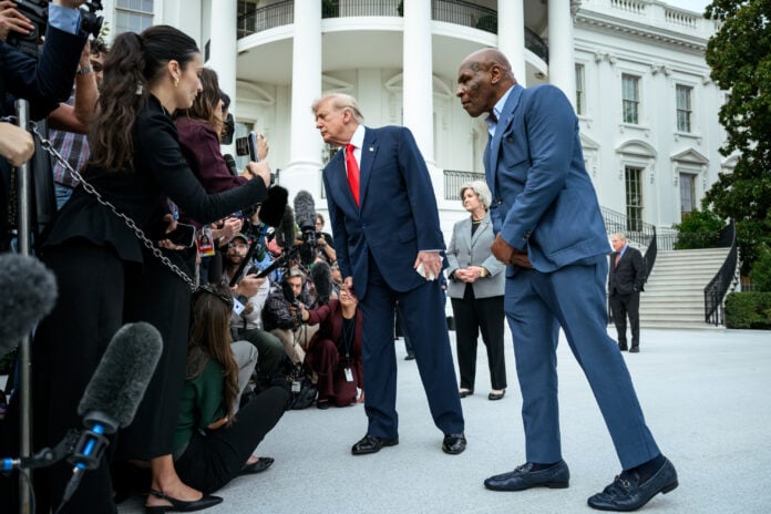 President Trump leans toward a crowd of reporters and microphones on the White House South Lawn, with Mike Tyson standing beside him