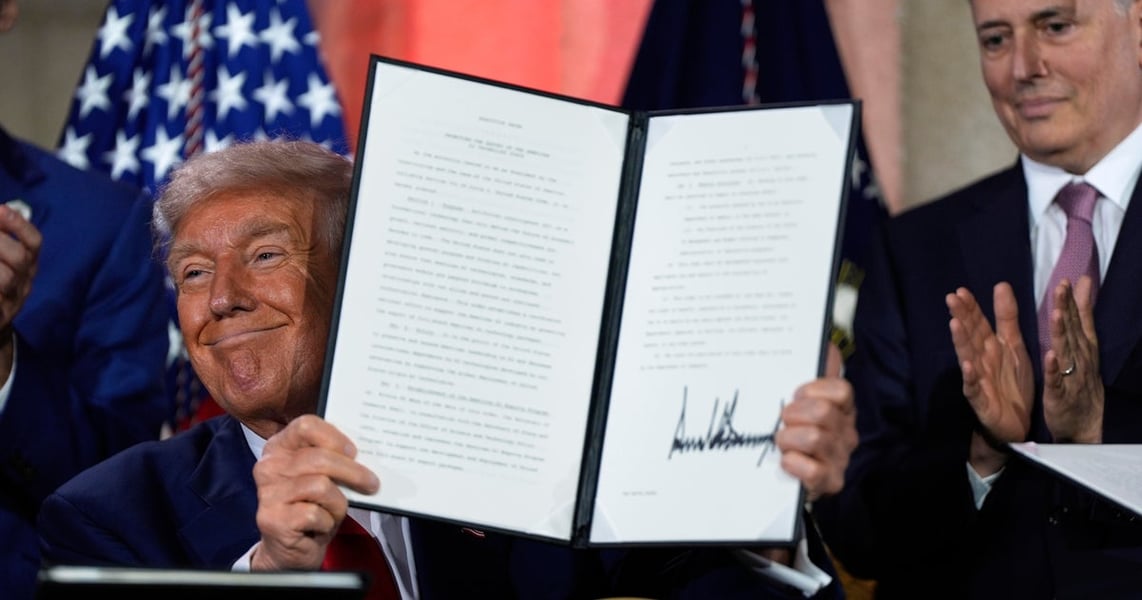 President Donald Trump holding up a signed executive order at a White House ceremony