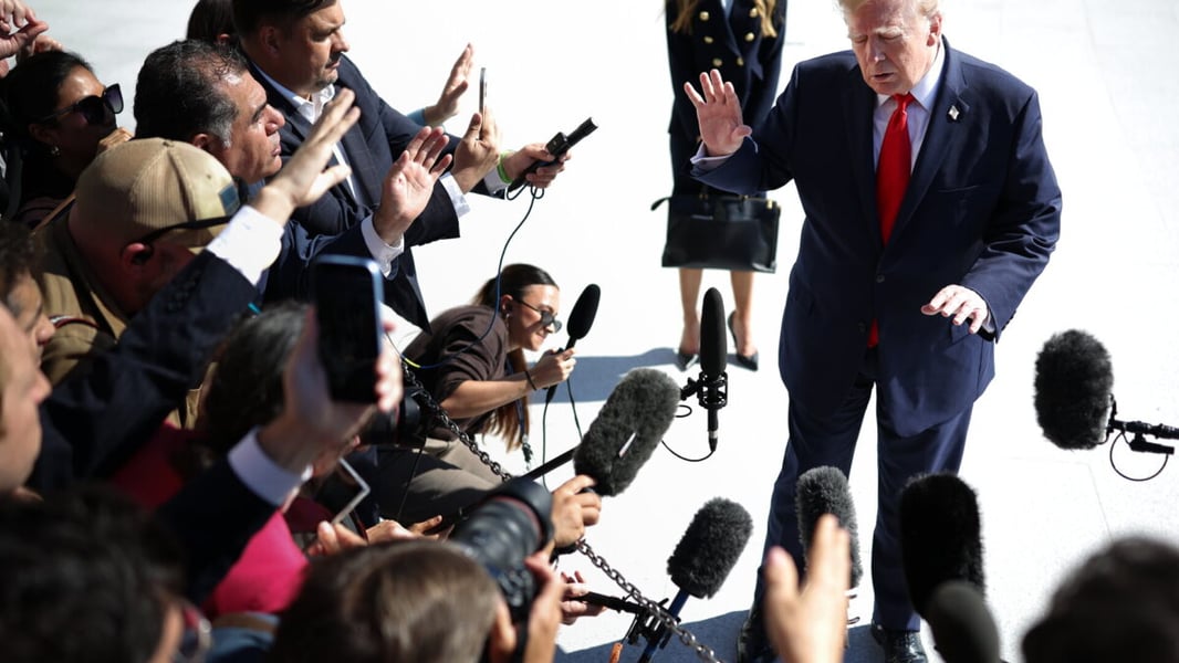 President Donald Trump speaks to reporters as microphones are held toward him on the South Lawn
