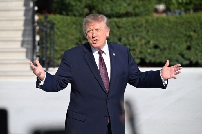 President Donald Trump gesturing with both hands as he speaks outdoors