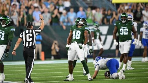 Tulane defender Jah'rie Garner, number 48, roars with fists clenched as a Memphis player kneels on the turf at Yulman Stadium