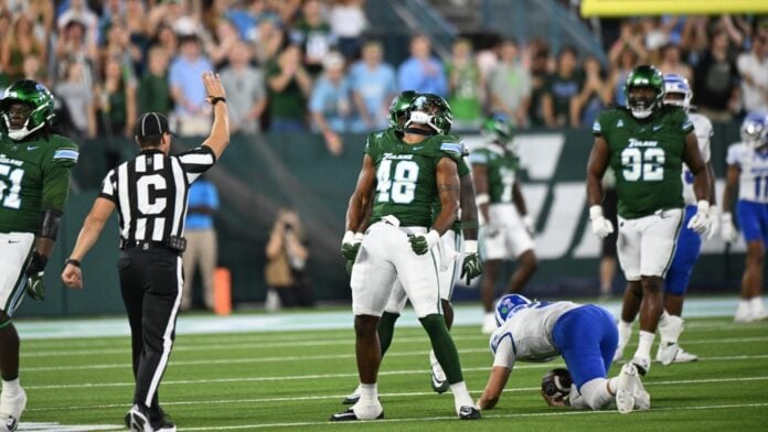Tulane defender Jah'rie Garner, number 48, roars with fists clenched as a Memphis player kneels on the turf at Yulman Stadium