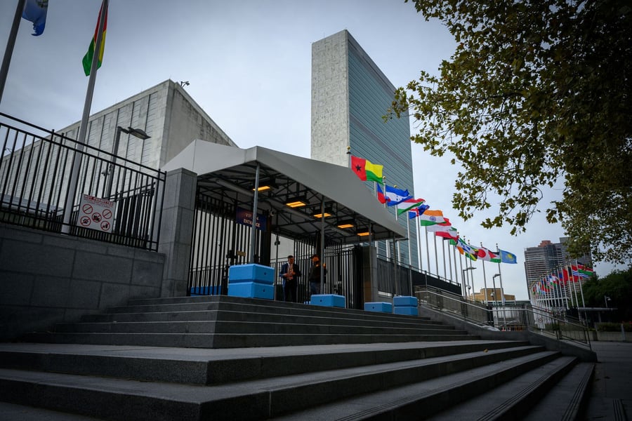 Entrance to United Nations Headquarters in New York with member state flags and the Secretariat building behind
