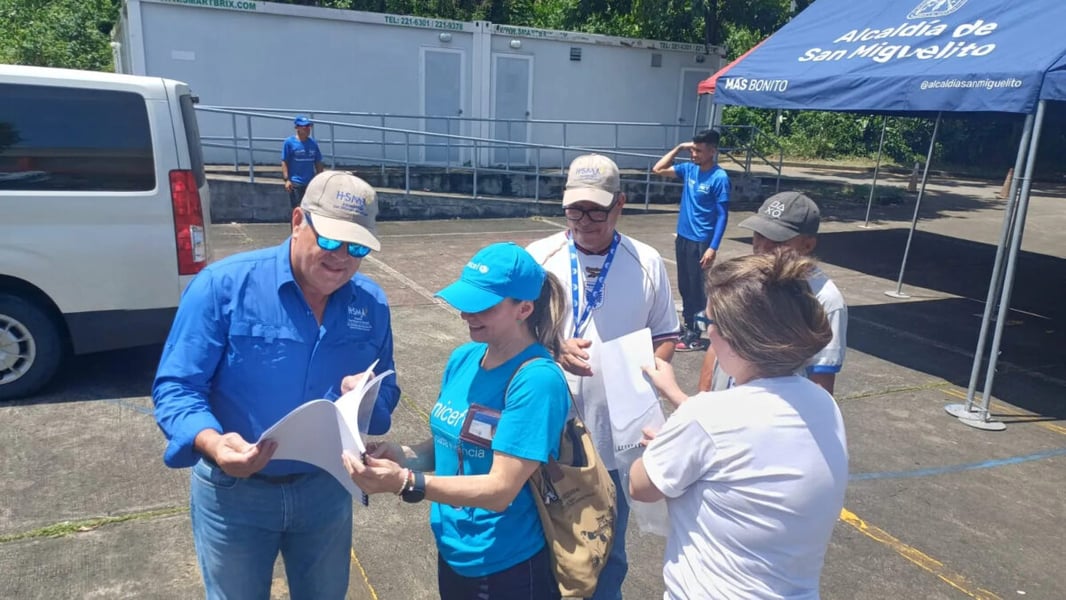UNICEF staff and health officials review papers beside a tent in a car park in San Miguelito