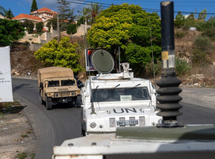 A white UN vehicle marked UNIFIL on a road in southern Lebanon with a Lebanese army truck ahead
