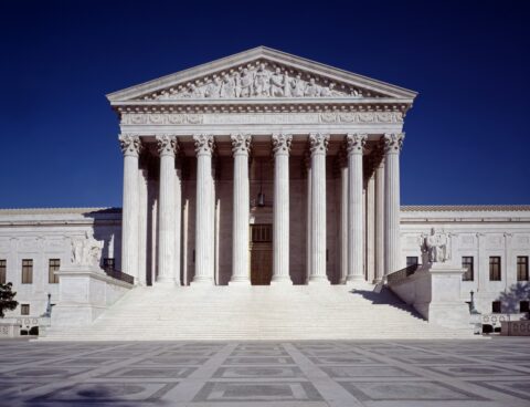 The marble front of the U.S. Supreme Court building with its columns, pediment and wide steps under a deep blue sky