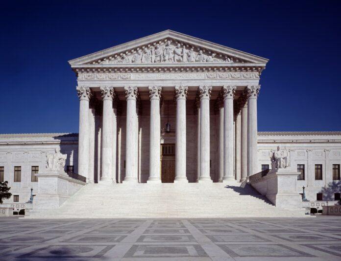 The marble front of the U.S. Supreme Court building with its columns, pediment and wide steps under a deep blue sky