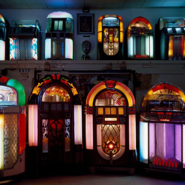 Rows of illuminated vintage Wurlitzer jukeboxes lining the walls of a jukebox museum