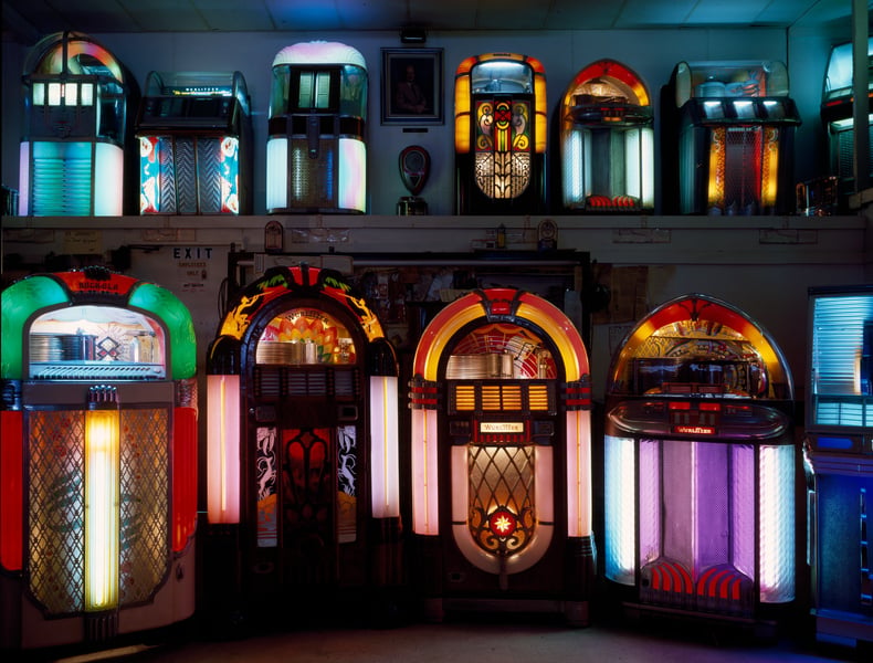 Rows of illuminated vintage Wurlitzer jukeboxes lining the walls of a jukebox museum