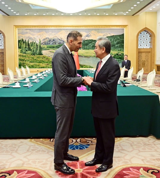 Wang Yi shakes hands with UAE special envoy Khaldoon Khalifa Al Mubarak in a Beijing meeting room