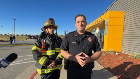 A Wichita police captain in uniform stands beside a firefighter in turnout gear during a media briefing