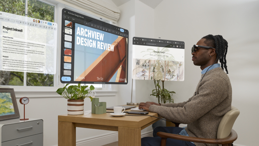 Person wearing Xreal Aura glasses at a desk with illustrative floating app windows