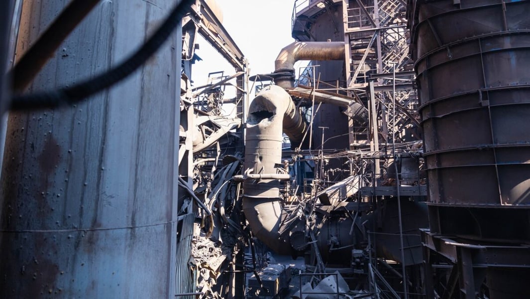 Twisted pipework and damaged steel structures between two large cylindrical vessels at the Zaporizhstal plant