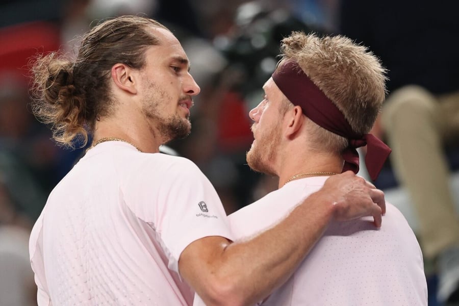 Alexander Zverev, left, with his arm around an opponent in a pink shirt and maroon headband at the net at the Shanghai Masters